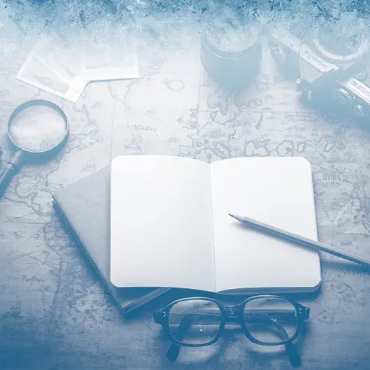 Ein Notizbuch und verschiedene Reiseuntensilien auf einer Landkarte